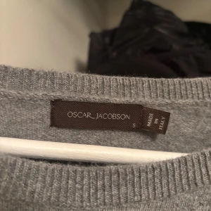 Grå tröja från Oscar Jacobson - Säljer en stilren grå tröja från Oscar Jacobson. Tröjan är tillverkad i Italien och har en klassisk design med rund hals och långa ärmar. Perfekt för en elegant och avslappnad look.