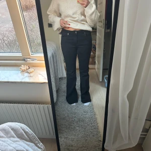 Svarta bootcut jeans - Snygga svarta bootcut jeans med låg midja. Perfekta för en stilren look. De har klassiska fem fickor och en knappgylf. Små i storleken skulle säga M/L