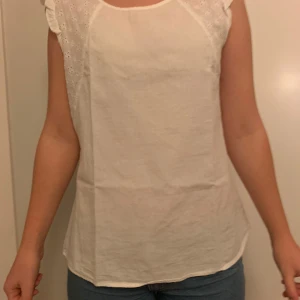 Vit blus - Säljer en söt vit blus med spetsdetaljer på axlarna. 
