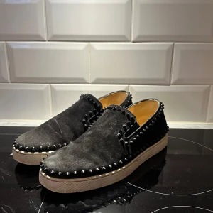 Christian Louboutin Slip-on - Snygga svarta loafers i mocka med nitar runt kanterna och den ikoniska röda sulan. Box och kvitto finns, dessa är väldigt eftertraktade! Går för 11k på Vestiaire!!! Kom med bud!