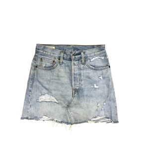 Blå jeanskjol - Snygg blå jeanskjol med slitna detaljer och rå kant. Kjolen har en klassisk femficksdesign och en dragkedja fram. Perfekt för en avslappnad stil.