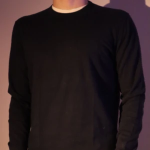 Svart tröja från Massimo Dutti - Snygg svart tröja från Massimo Dutti i bomull. Perfekt för en stilren look med långa ärmar och rund hals. Passar bra till både vardag och mer uppklädda tillfällen.