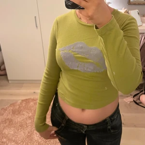 Cool topp!! - Skit cool grön tröja med ett lila/blå läpp tryck, säljer då den inte riktigt är min stil. Använd fåtal gånger endast och är i bra skick utan några defekter 💚💚
