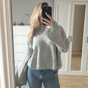 Grå stickad tröja - Mysig grå stickad tröja med oversized passform och långa ärmar. Perfekt för kyliga dagar och ger en avslappnad look. Passar bra till jeans eller leggings.
