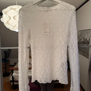 Vit spetsblus - Elegant vit spetsblus med långärmad design. Perfekt för att lägga till en romantisk touch till din outfit. Blusen har ett vackert spetsmönster som ger en feminin känsla.