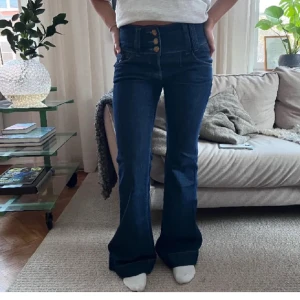 Blå bootcut jeans med knappar - Snygga blå bootcut jeans med dekorativa knappar framtill. Bilderna är från köparen. Säljer på grund av att de inte passade mig så bra! 😊 