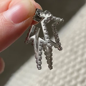 Silvriga blixtformade örhängen - Snygga silvriga örhängen i form av blixtar med glittrande detaljer. Aldrig använda