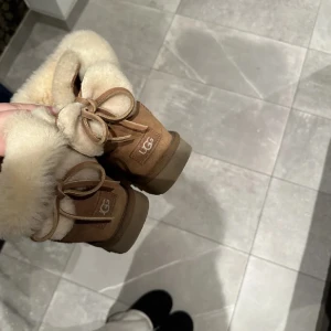 Bruna boots från UGG - Säljer ett par klassiska bruna UGG boots med mjukt pälsfoder och snörning. Perfekta för kalla dagar med sin varma och bekväma design.