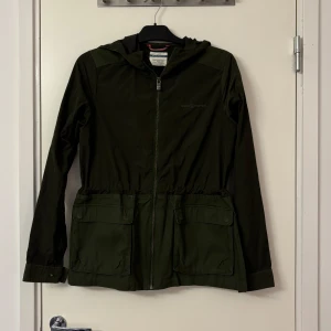 Grön vindjacka från Race Marine - Snygg grön vindjacka från Race Marine med huva och dragkedja framtill. Jackan har praktiska fickor och justerbar midja för en bekväm passform. Perfekt för blåsiga dagar.