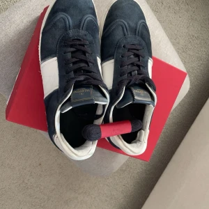  Valentino flycrew - Säljer ett par snygga sneakers från Valentino i blått och vitt. De är gjorda i mocka och har en klassisk snörning. Skorna är i nyskick och kommer i originalkartong. Perfekta för både vardag och fest!