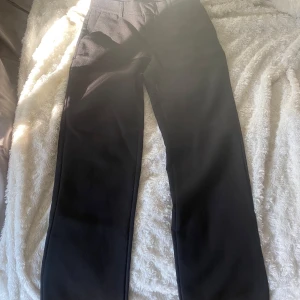 Lågmidjade kostymbyxor  - Lågmidjade svarta kostymbyxor från nelly. Storlek 34. De är uppsydda i benen och passar bra för någon som är ca 168 eller kortare. De är något slitna(se sista bilden). Hör av er för mer bilder. Kan säljas billigare vid snabb och smidig affär. Finns på vinted också