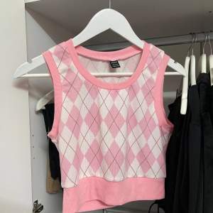 Säljer en superfin rosa och vit rutig topp från Shein. Den är ärmlös och har en croppad passform, perfekt för styling plagg på plagg. Toppen är i ett mjukt och bekvämt material, perfekt för både vardag och fest!