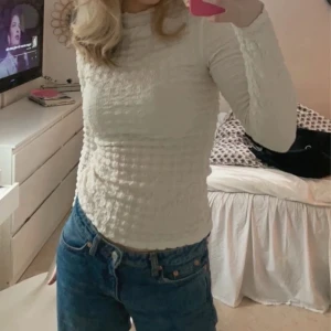 Vit ribbad långärmad topp - Säljer en stilren krämvit ribbad topp med långa ärmar. Perfekt för en enkel och elegant look. Passar bra till jeans eller kjol.