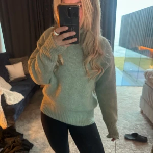 Grön stickad tröja - Mysig grön stickad tröja med långa ärmar och ribbade muddar. Perfekt för kyligare dagar och ger en avslappnad look. Passar bra till jeans eller leggings.
