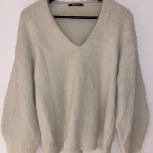 Beige stickad tröja från Gina Tricot - Mysig beige stickad tröja från Gina Tricot med v-ringning. Perfekt för kyliga dagar med sin fluffiga textur och långa ärmar. En stilren och bekväm tröja som passar till många tillfällen.