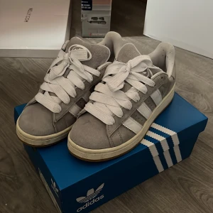 Grå Adidas sneakers - Snygga gråa Adidas campus 00. Jag säljer de eftersom de aldrig kommer till användning. De är i jättebra skick och har med både gråa och vita skosnören. 