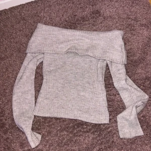 Grå offshoulder stickad tröja - Säljer en grå stickad tröja med offshoulder-design. Bara använt ett fåtal gånger så jättebra skick! ❤️