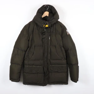 Parajumpers Harraseeket XL slumfit - Säljer en snygg mörkgrön dunjacka från Parajumpers med broderad patch på ärmen. Jackan har en hög krage och praktiska fickor med dragkedja. Använd men i nyskick. Passar L-XL