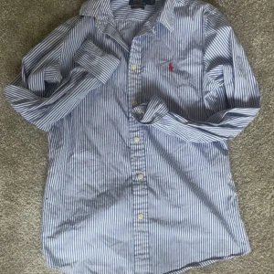 Randig skjorta från Ralph Lauren - Hej! Säljer nu min fina Ralph lauren skjorta då jag inte har behov av den längre. Passar xs och s. Skicket är 8/10 använts men inga tecken. Perfekt nu för sommaren eller för fester! Hör av er om ni funderar över något.