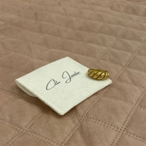 Guldfärgad ring med vridet mönster - Elegant guldfärgad ring med ett unikt vridet mönster. Perfekt för att ge en stilfull touch till din outfit. Kommer med en liten förvaringspåse. (Rostfritt stål)