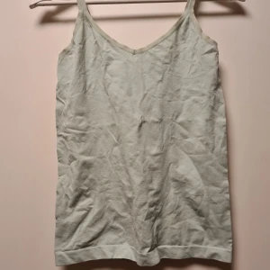 Ljusgrönt sportlinne - Säljer en enkel och stilrent ljusgrönt linne. Toppen har en v-ringad design och är tillverkad i ett mjukt material som känns skönt mot huden. Perfekt för att sporta i, varma dagar eller som ett basplagg i garderoben.