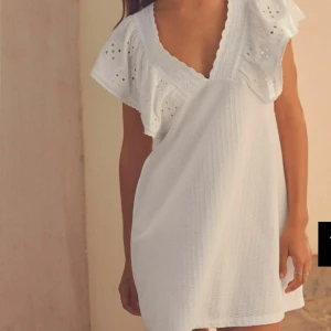 Vit klänning med spetsdetaljer - Slutsåld på zalando. Köpte den för 600 och säljer för 550 helt oanvänd och superfin klänning. Jättefina spetsdetaljer och v-ringad design💕Klänningen har en öppen rygg med knytband och korta ärmar