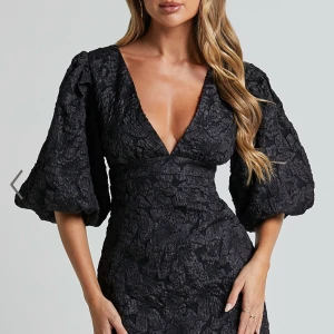 Showpo klänning med puffärm - Elegant svart klänning med djup v-ringning och puffiga trekvartsärmar. Använd 1 gång( pris kan diskuteras vid snabb affär)