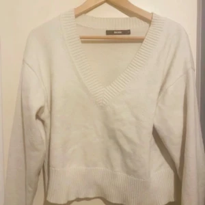 Vit stickad tröja från Bik Bok - Säljer en vit stickad tröja från Bik Bok med v-ringning. Tröjan har långa ärmar och ribbade kanter vid hals och nederkant. Perfekt för kyligare dagar. 