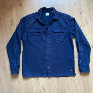 Overshirt - Hej, säljer en navy blue overshirt i strlk S. Den stängs med knappar och den har två bröstfickor.                 Den är även uppknäppbar vid handleden så man kan minska längden på den om man så vill. Inga defekter, perfekt nu till våren! 🤩