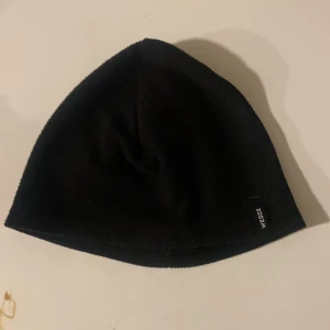 Svart mössa från Wed'ze - Snygg och enkel svart mössa från Wed'ze. Perfekt för kyliga dagar med sin stilrena design. Passar bra till både vardag och utomhusaktiviteter.