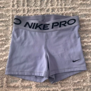 Grå träningsshorts från Nike - Snygga grå träningsshorts från Nike med elastisk midja och Nike Pro-logga. Perfekta för intensiva träningspass. De har en tight passform och är tillverkade i ett mjukt och stretchigt material för maximal komfort. Storlek L men är små i storlek och passar M - S då de är stretchiga💙 40cm rakt över 