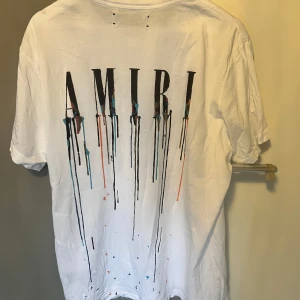 Vit t-shirt från Amiri med tryck - Säljer en vit t-shirt från Amiri med ett coolt tryck av droppande färg på både fram- och baksidan.