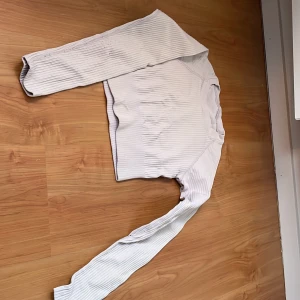 Vit ribbad tröja - Säljer en stilren vit ribbad tröja med långa ärmar. Tröjan har en enkel design med rund hals och ribbade detaljer som ger en snygg textur. Perfekt för en avslappnad look.