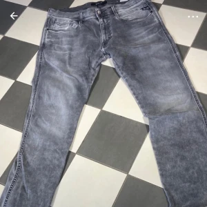 Grå jeans från Replay - Snygga grå jeans från Replay i modellen Anbass. De har en klassisk femficksdesign och en bekväm passform. Perfekta för en stilren look.