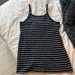 Randig linnetopp från Gando - Säljer en randig linnetopp från Gando i mörkblått och vit. Toppen har smala axelband och är tillverkad i 100% bomull. Perfekt för en avslappnad stil.💕