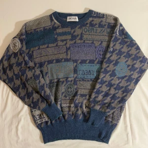 Vintage Stickad Tröja från Hugo Boss - Säljer en unik mönstrad tröja från Hugo Boss i blå och grå toner. Gjord i West-Germany vid 80-talet! Tröjan har ett iögonfallande geometriskt mönster och är långärmad med ribbade muddar vid ärmslut och nederkant. Perfekt för dig som vill sticka ut med stil. Storlek: M-L (Chest 50) 