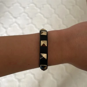 Valentino liknande armband - Snyggt svart armband med guldiga nitar. Liknar Valentino armbanden men är från märket DARK.  Armbandet är i nyskick. Armbandet har en justerbar rem med flera hål för perfekt passform. 