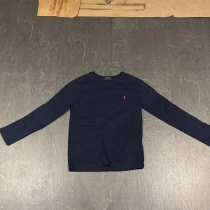 Mörkblå långärmad tröja från Ralph Lauren - Säljer en stilren mörkblå långärmad tröja från Ralph Lauren. Skick är 10/10, några funderingar så är det bara att skriva 