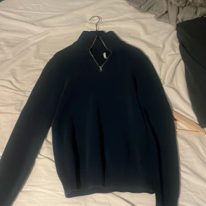 Mörkblå tröja med dragkedja - Säljer en stilren mörkblå tröja med dragkedja vid halsen. Perfekt för en avslappnad look. Tröjan har långa ärmar och en enkel design som passar till det mesta.