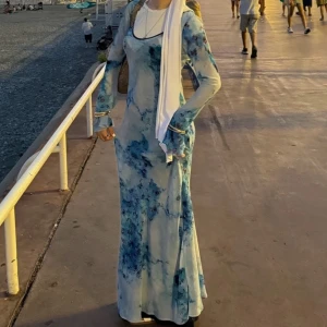 Blå långklänning med blommigt mönster - Jättefin maxiklänning med långa utsvängda ärmar och en elegant v-ringning från Topshop! Använd endast en gång på semester, så nästan ny skick! Mörkblå underklänning följer med! Den har inga skador alls, jätteskönt material! OBS: på bilden har jag en vit T-shirt under då det är urringat annars!  Tveka inte att skriva om ni har några frågor!