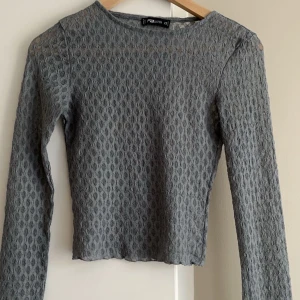 Grå spetsblus från NEW YORKER - Säljer en elegant grå spetsblus från NEW YORKER. Blusen har ett vackert spetsmönster och långa ärmar, perfekt för en stilren look. Passar utmärkt till både vardag och festliga tillfällen. (EGNA BILDER PRIVAT) 