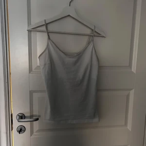 Vit linnetopp - Säljer en enkel och stilren vit linnetopp med tunna axelband. Perfekt för varma dagar eller som lager under andra plagg.