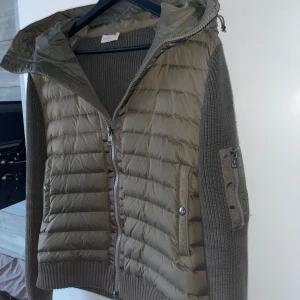 Moncler Cardigan - Snygg olivgrön cardigan från Moncler. Jackan har dragkedja framtill och praktiska fickor med knappar. Perfekt till våren med sin kombination av stil och funktion. Storlek L men passar som M. Pris ej hugget i sten! Skriv järna om du undrar något! 