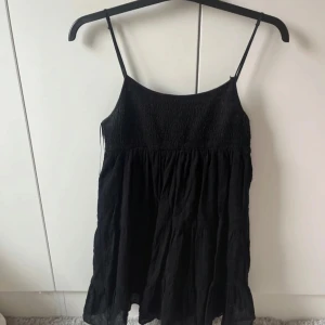 Svart  klänning - Snygg svart klänning med volang nertill, små tecken på användning upptill, annars inga defekter 