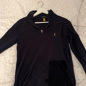Marinblå halfzip från Ralph Lauren - Säljer en stilren marinblå halfzip tröja från Ralph Lauren. passar en som är runt 155-162