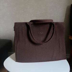 Brun shoppingväska från LXA - Säljer en brun shoppingväska från LXA. Använd fåtal gånger men formen är lite skev, se kvalite på bilderna🤍
