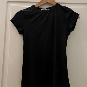 Svart kortärmad topp - Säljer en stilren svart topp med korta ärmar. Perfekt för en minimalistisk look och lätt att matcha med olika outfits. Ny. Inköpt fel storlek. Storlek M