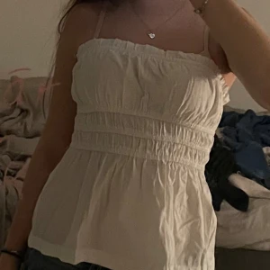 Vit tubtopp från Stradivarius - Säljer en söt vit tubtopp från Stradivarius. Toppen har en smockad design med elastiska detaljer för en bekväm passform. Perfekt för varma sommardagar eller som ett lager under en jacka.🫶