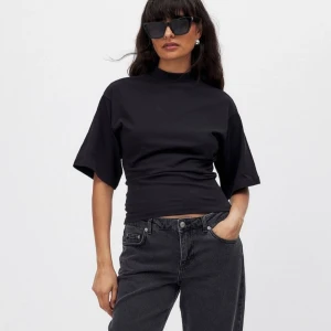 Svart kortärmad topp - Snygg svart topp med korta ärmar och hög hals. Perfekt för en stilren look. Toppen har en tight passform som framhäver figuren.