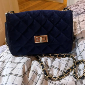 Svart quiltad axelväska i skinn(verapelle) - Snygg svart quiltad axelväska i  skinn, tillverkad i Italien. Väskan har en elegant kedjerem och ett stilrent spänne i metall. Perfekt för att ge din outfit en lyxig touch. Priset kan alltid diskuteras 